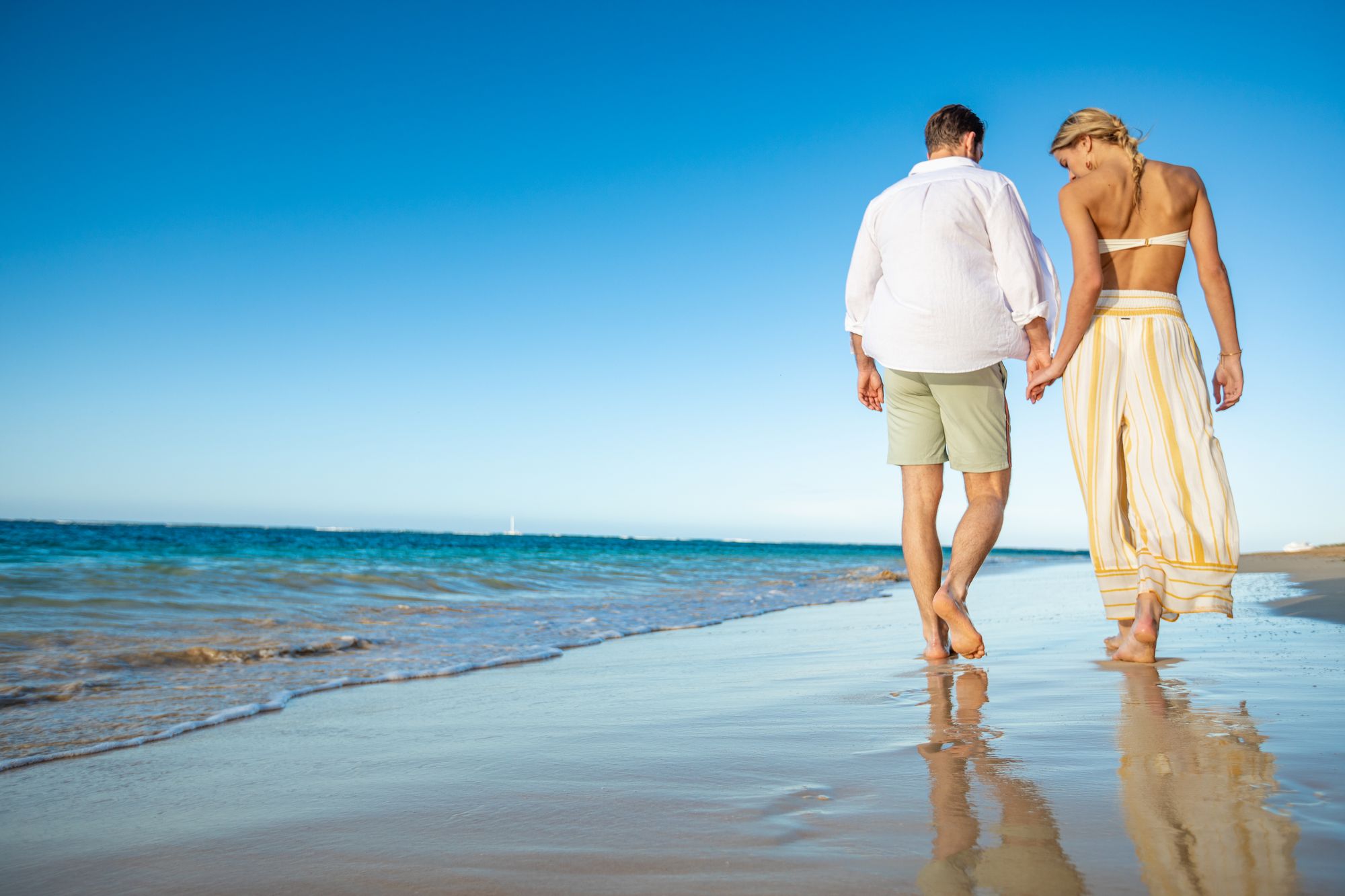 Couple walking hand in hand on Caribbean beach