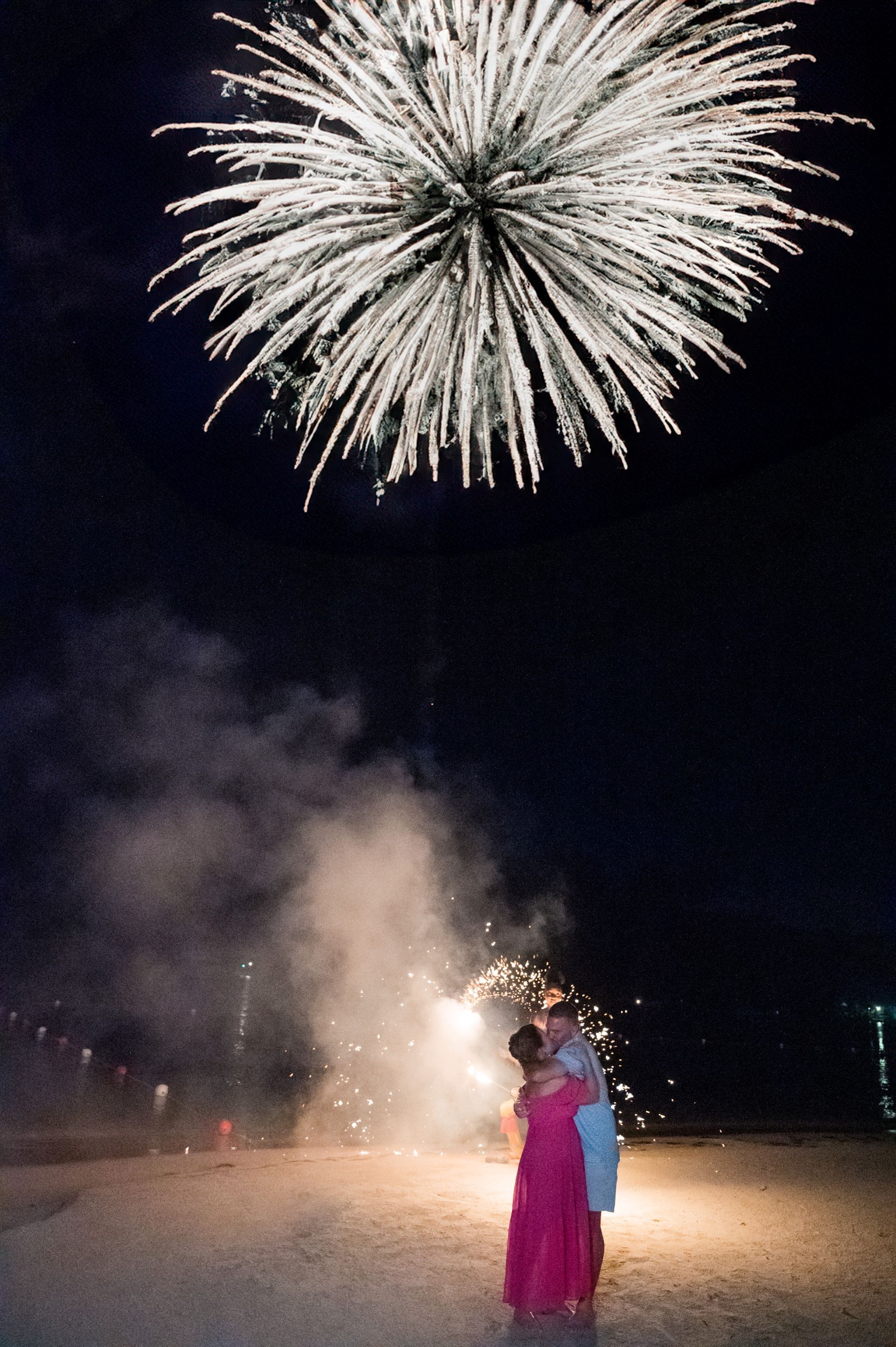 Couple embracing under fireworks on the beach at Sandals Negril