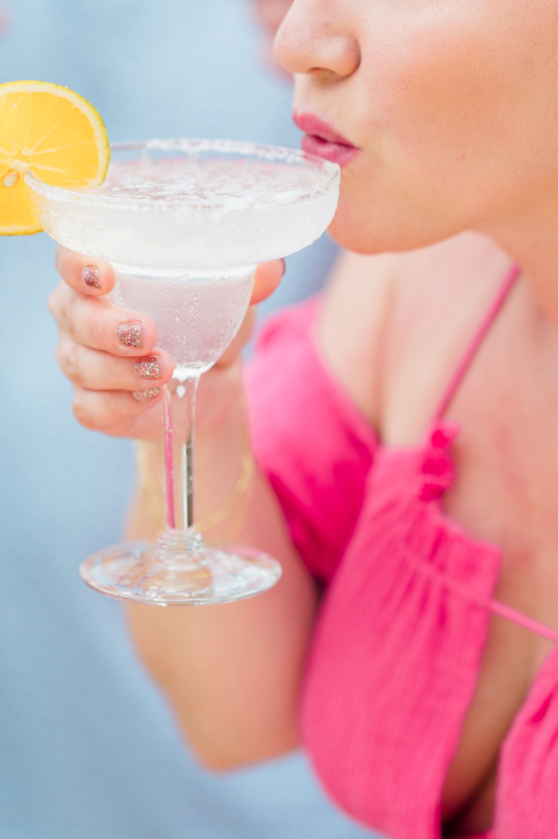 Morgan sipping a margarita with a slice of orange garnish